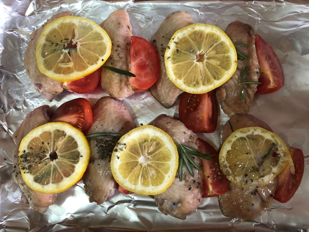 place chicken wings tomatoes lemon on the baking pan